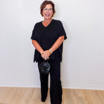 Woman wearing a black outfit against a white wall
