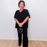 Woman wearing a black outfit against a white wall