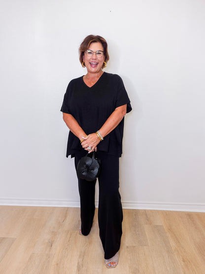 Woman wearing a black outfit against a white wall