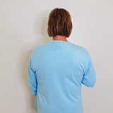 woman blue holiday knit top against a white background 