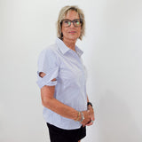 Woman wearing a light blue shirt and black skirt against a white wall