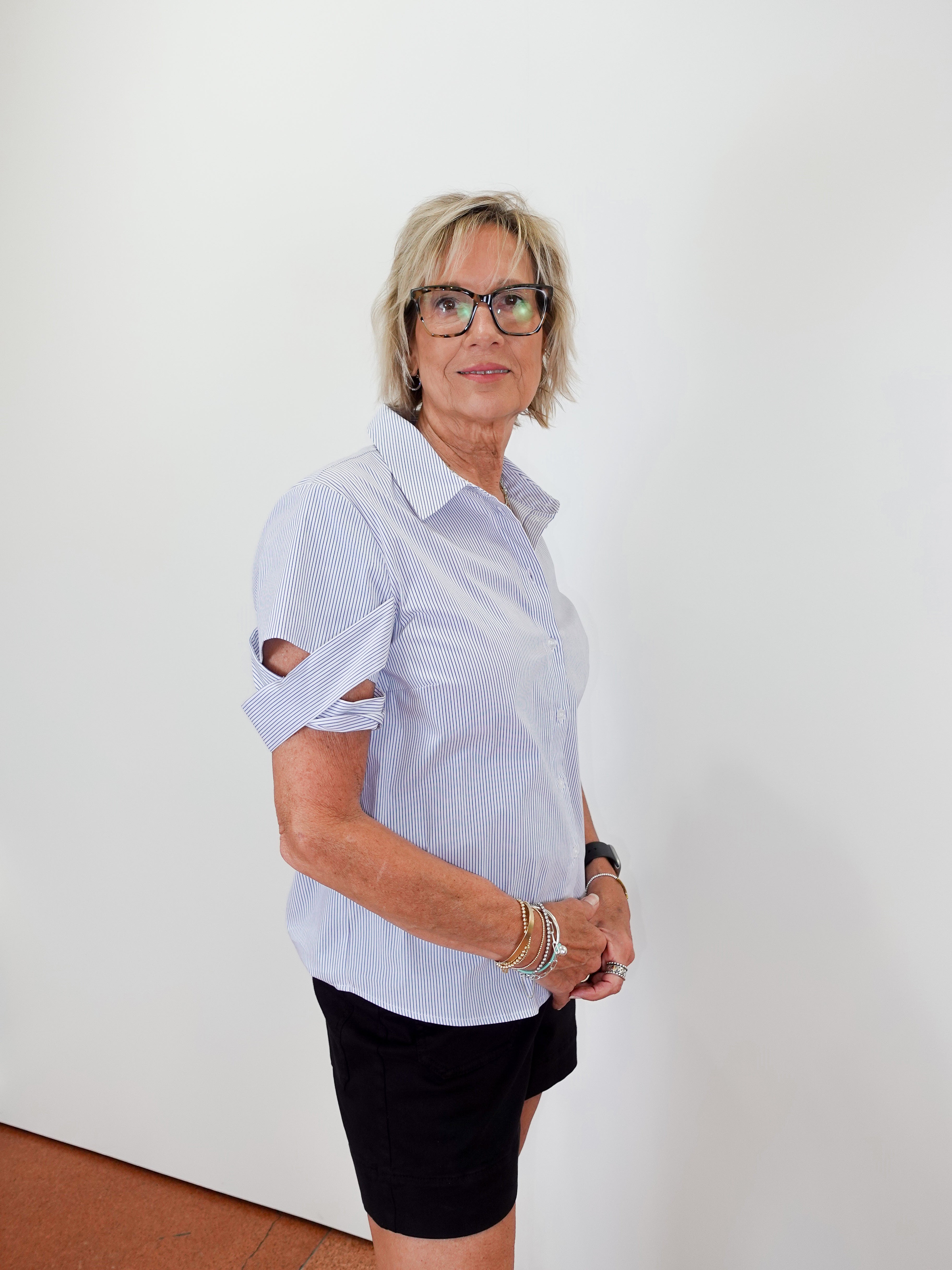 Woman wearing a light blue shirt and black skirt against a white wall