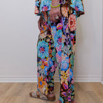 Person wearing colorful floral pants on a plain background