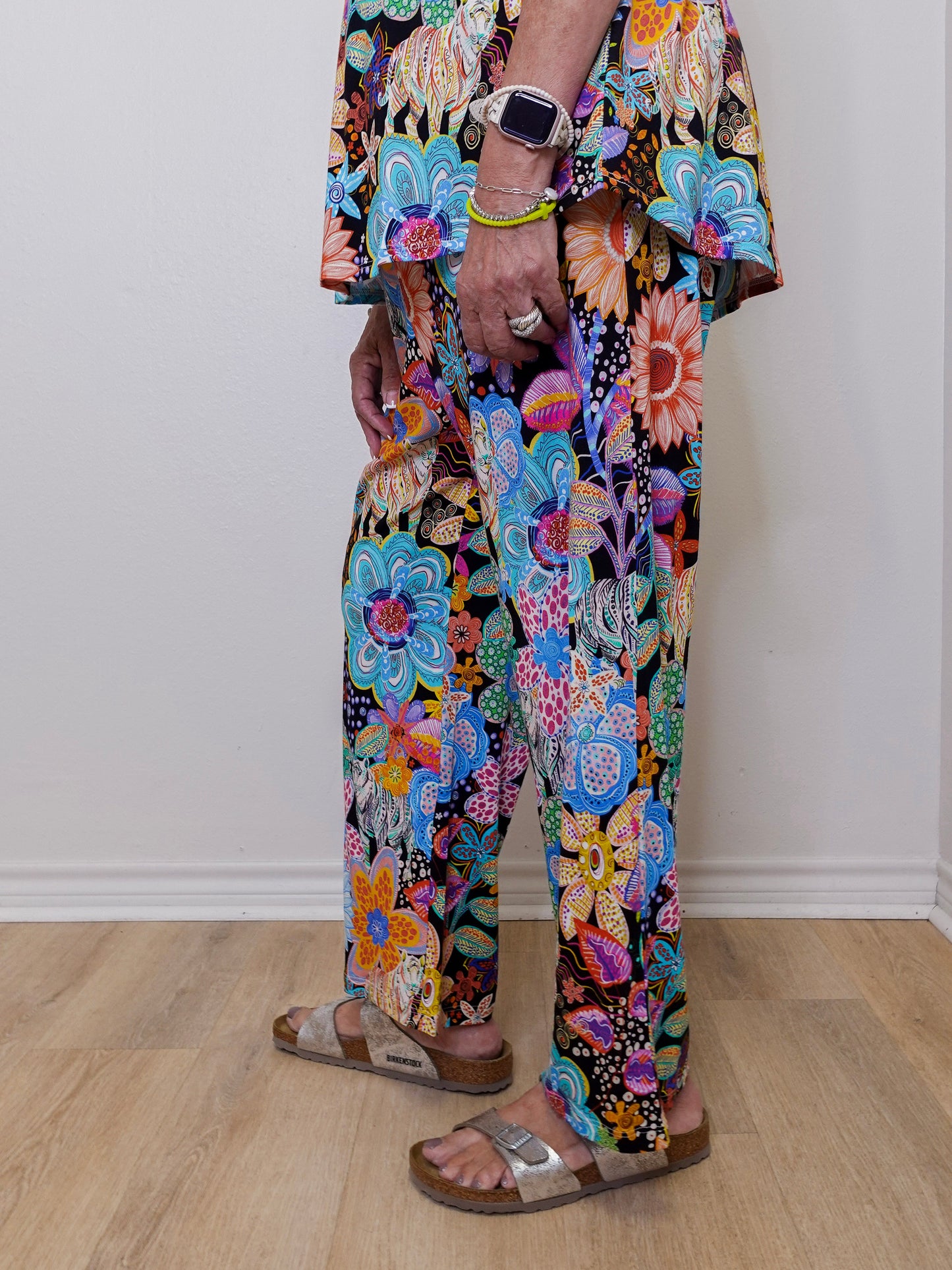Person wearing colorful floral pants on a plain background