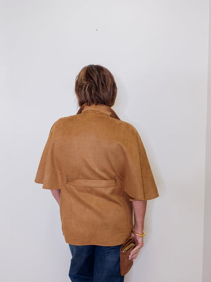 Person wearing a brown jacket against a white wall