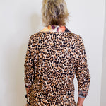 Person wearing a leopard print outfit with a white wall background