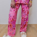 Person wearing pink floral pajama set with white shoes on a wooden floor.