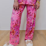 Person wearing pink floral pajama set with white shoes on a wooden floor.