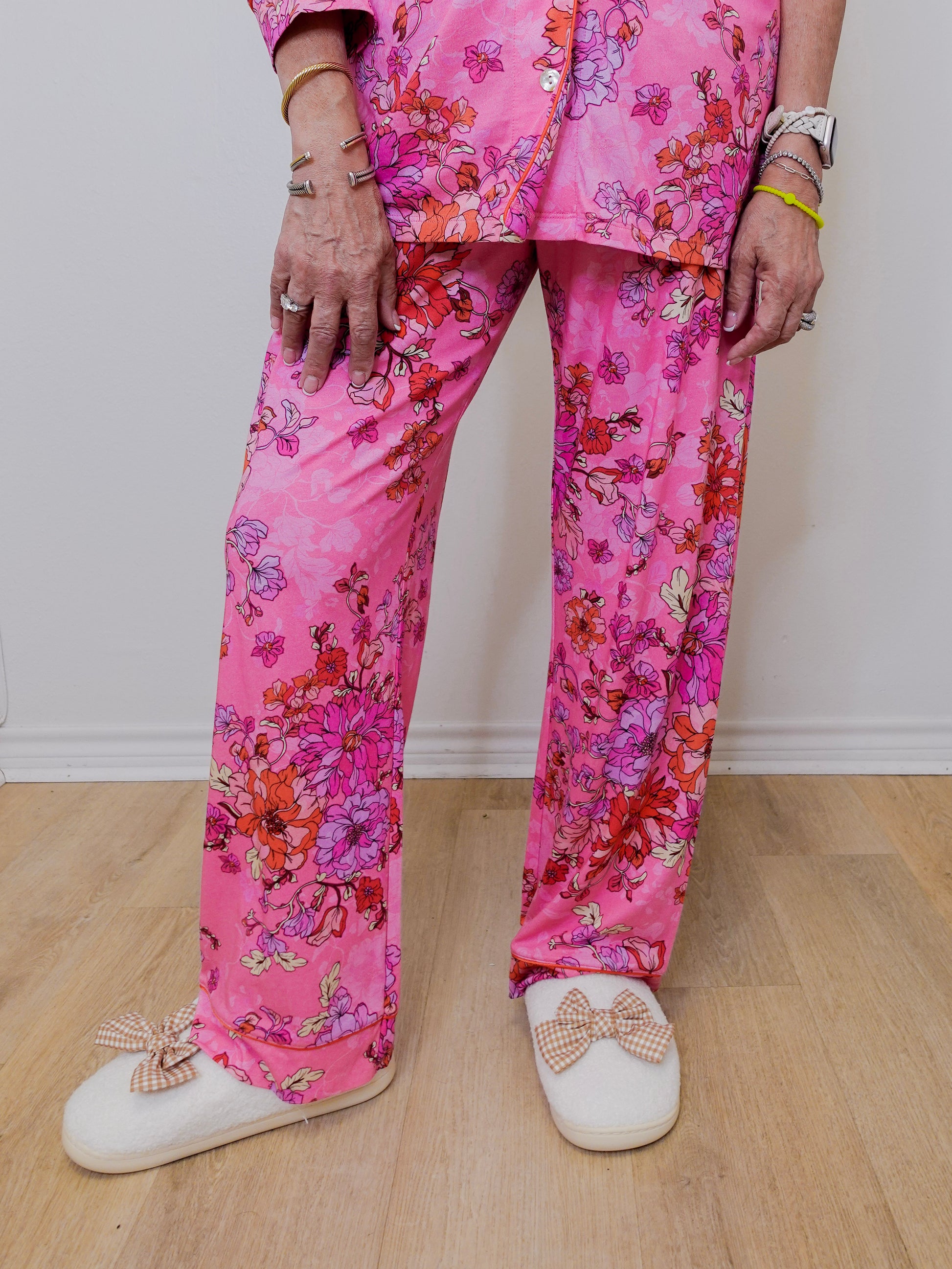 Person wearing pink floral pajama set with white shoes on a wooden floor.