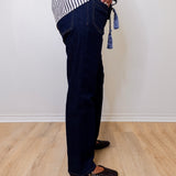 Person wearing dark blue jeans and a striped shirt on a light wooden floor.