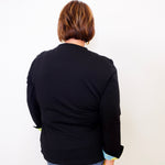 Person wearing a black jacket and blue jeans against a white background