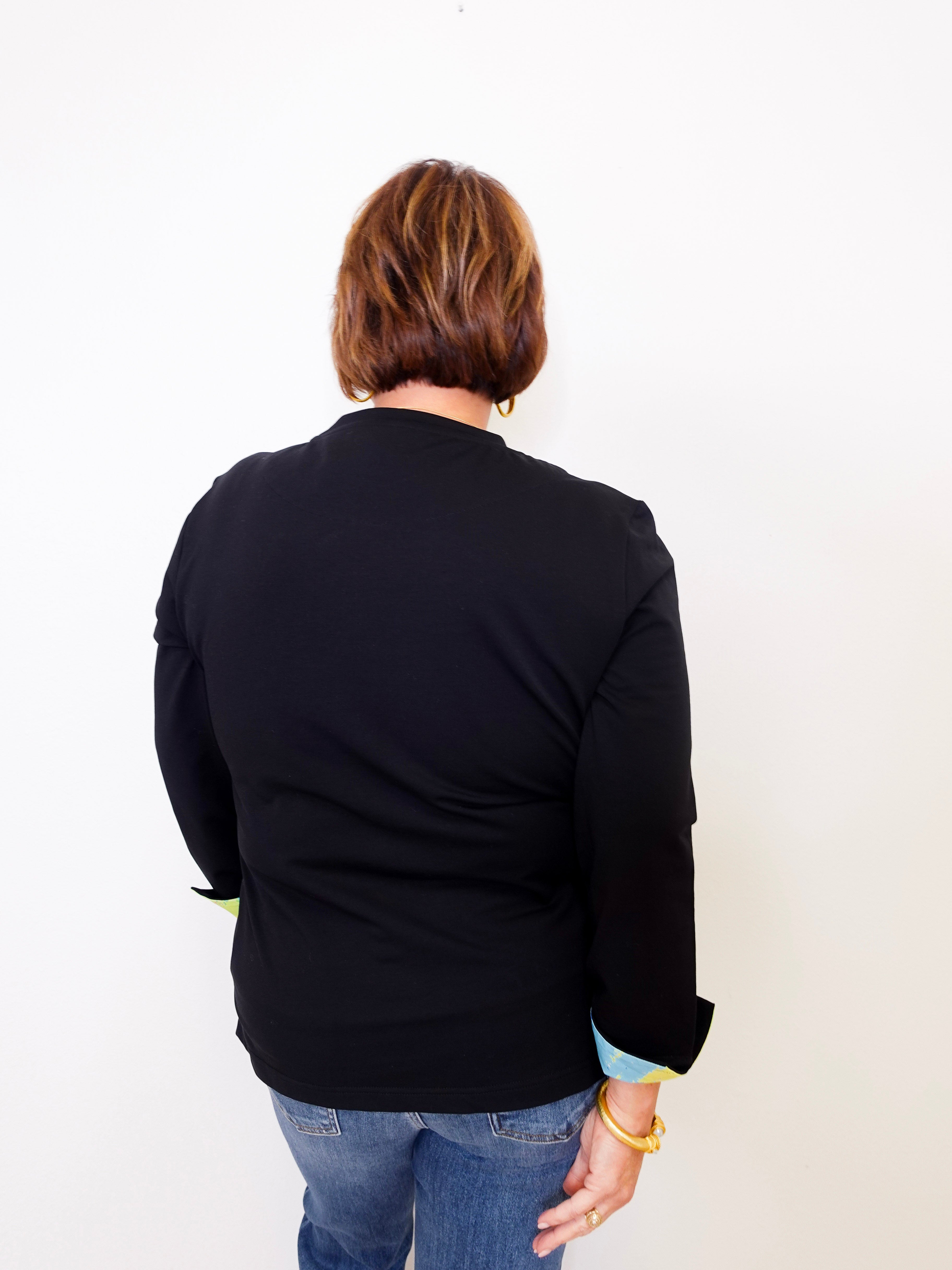 Person wearing a black jacket and blue jeans against a white background