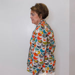 Woman wearing a colorful patterned jacket against a white wall
