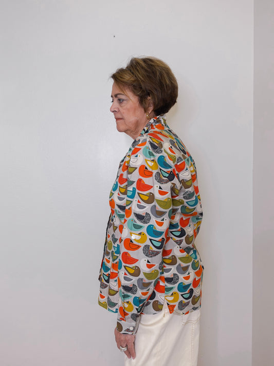 Woman wearing a colorful patterned jacket against a white wall