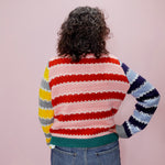 Person wearing a colorful striped sweater against a plain background