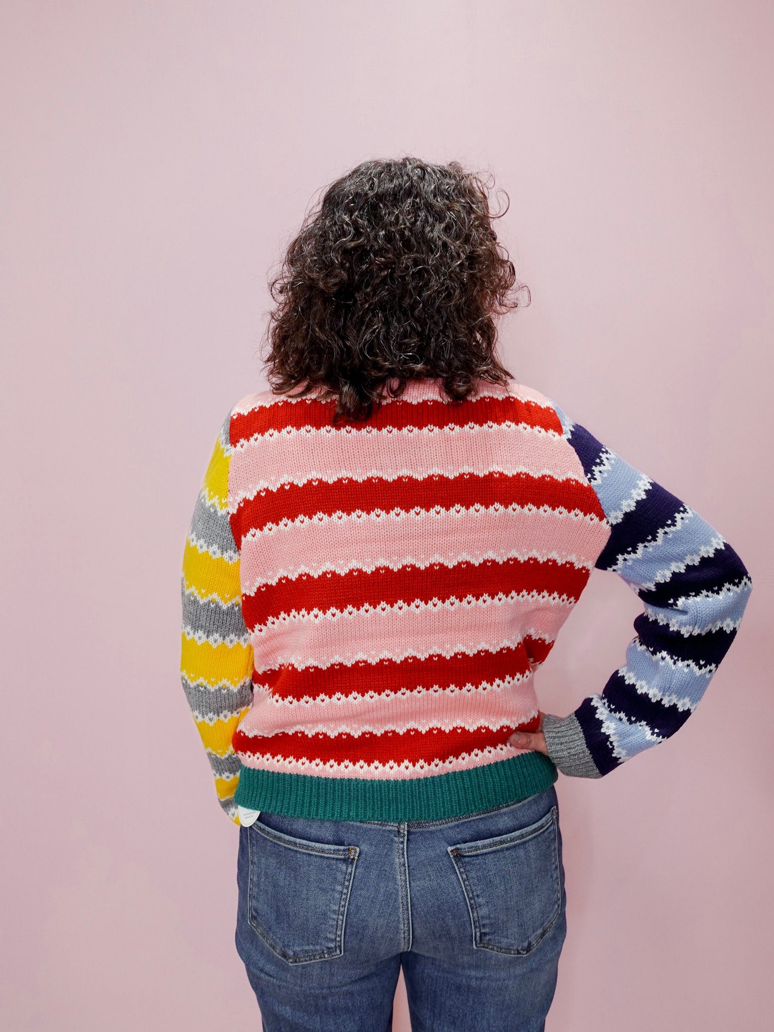 Person wearing a colorful striped sweater against a plain background