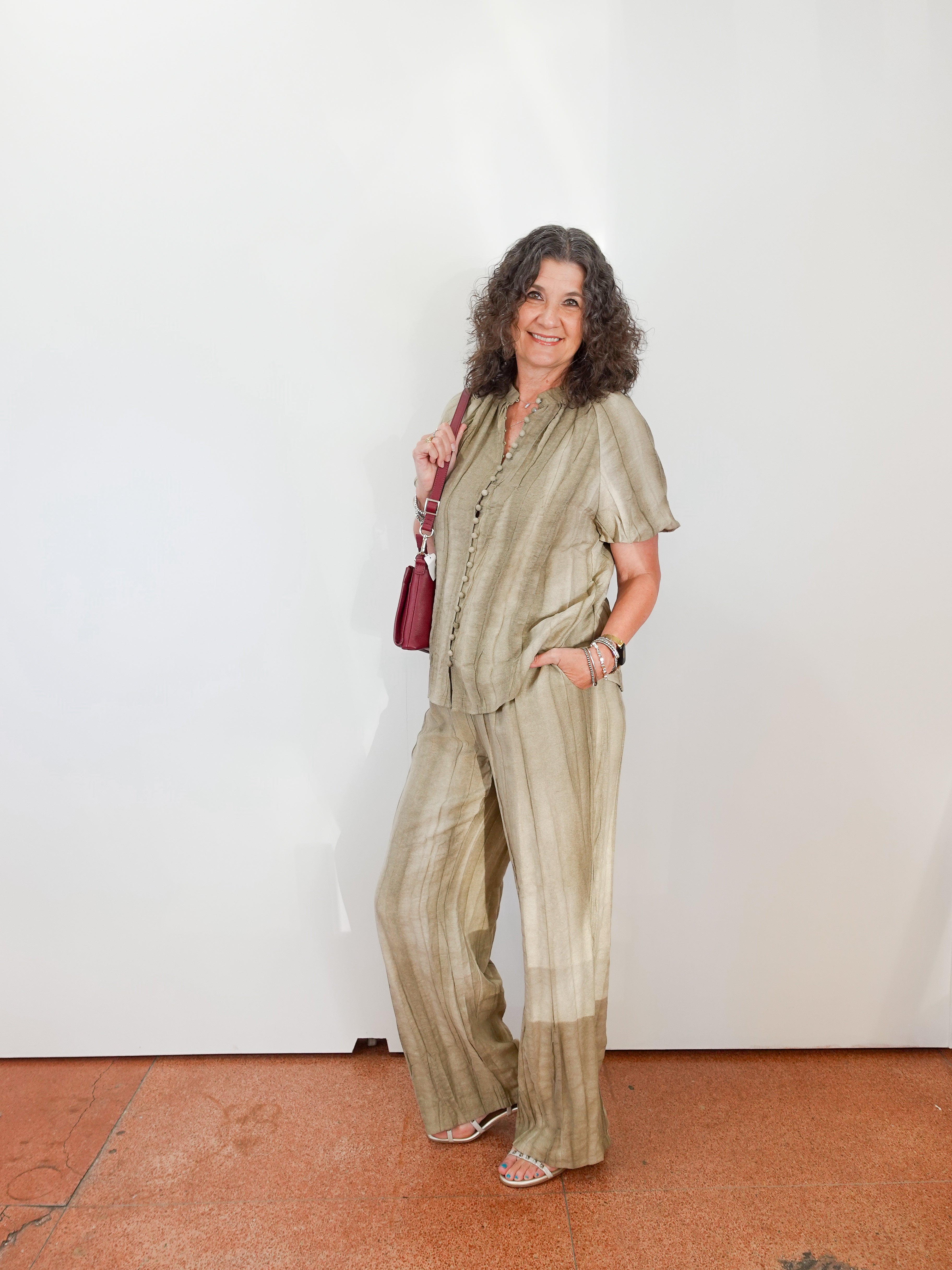 Woman wearing a green outfit with a white wall background