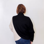 Person wearing a black and beige shirt with blue jeans on a white background