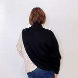 Person wearing a black and beige shirt with blue jeans on a white background