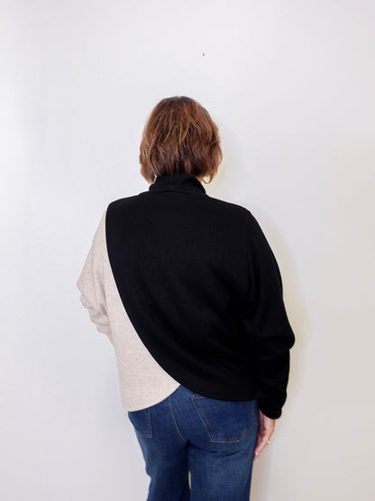 Person wearing a black and beige shirt with blue jeans on a white background