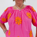 Woman wearing a pink blouse with orange floral patterns on a white background