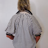 Person wearing a black and white striped shirt against a plain background