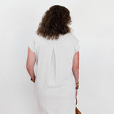 Person wearing a white dress standing against a plain background