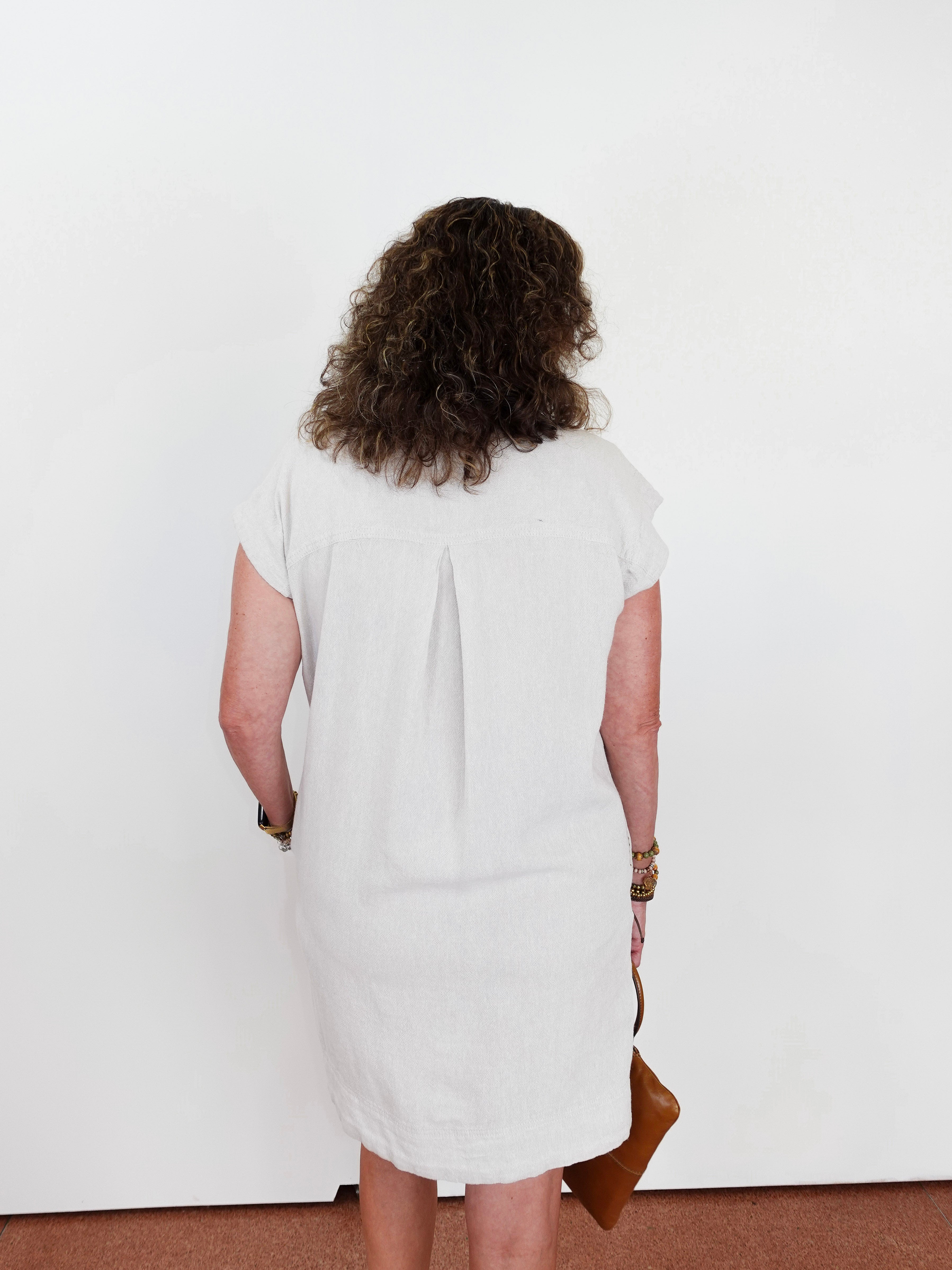 Person wearing a white dress standing against a plain background