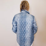 Person wearing a blue quilted jacket against a plain background