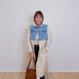 woman wearing a long denim mix trench coat against a white background 