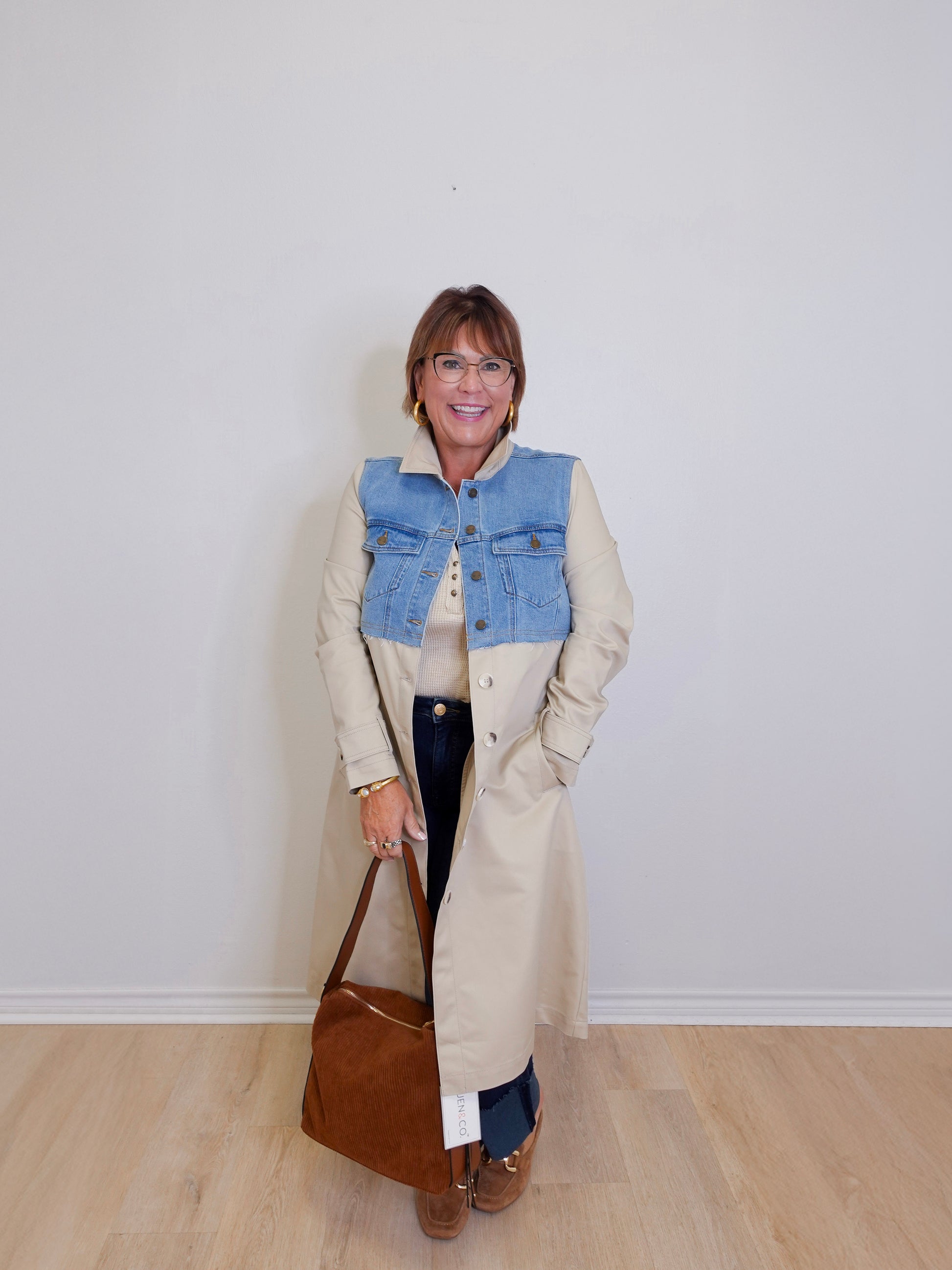 woman wearing a long denim mix trench coat against a white background 