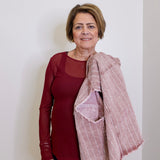 Woman wearing a red top and pink scarf against a white background