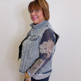 Woman wearing a denim vest over a patterned shirt against a plain background