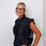 Woman wearing a black sleeveless shirt and glasses against a white background