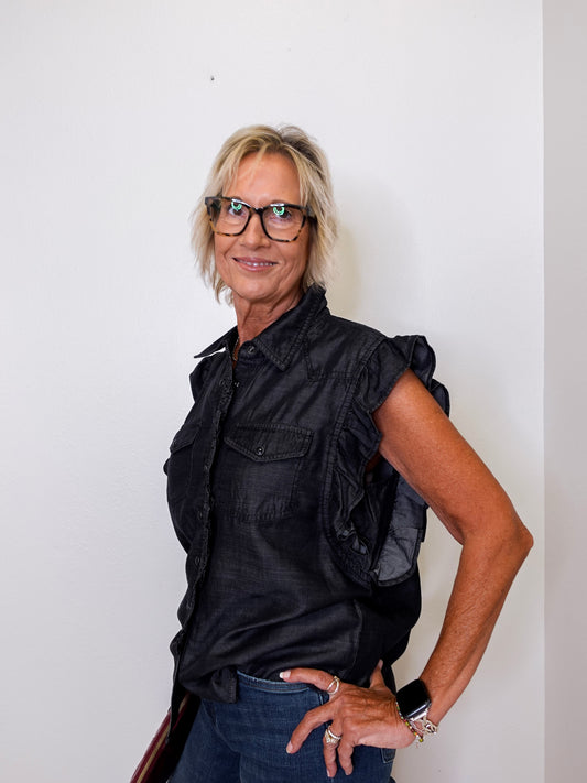 Woman wearing a black sleeveless shirt and glasses against a white background