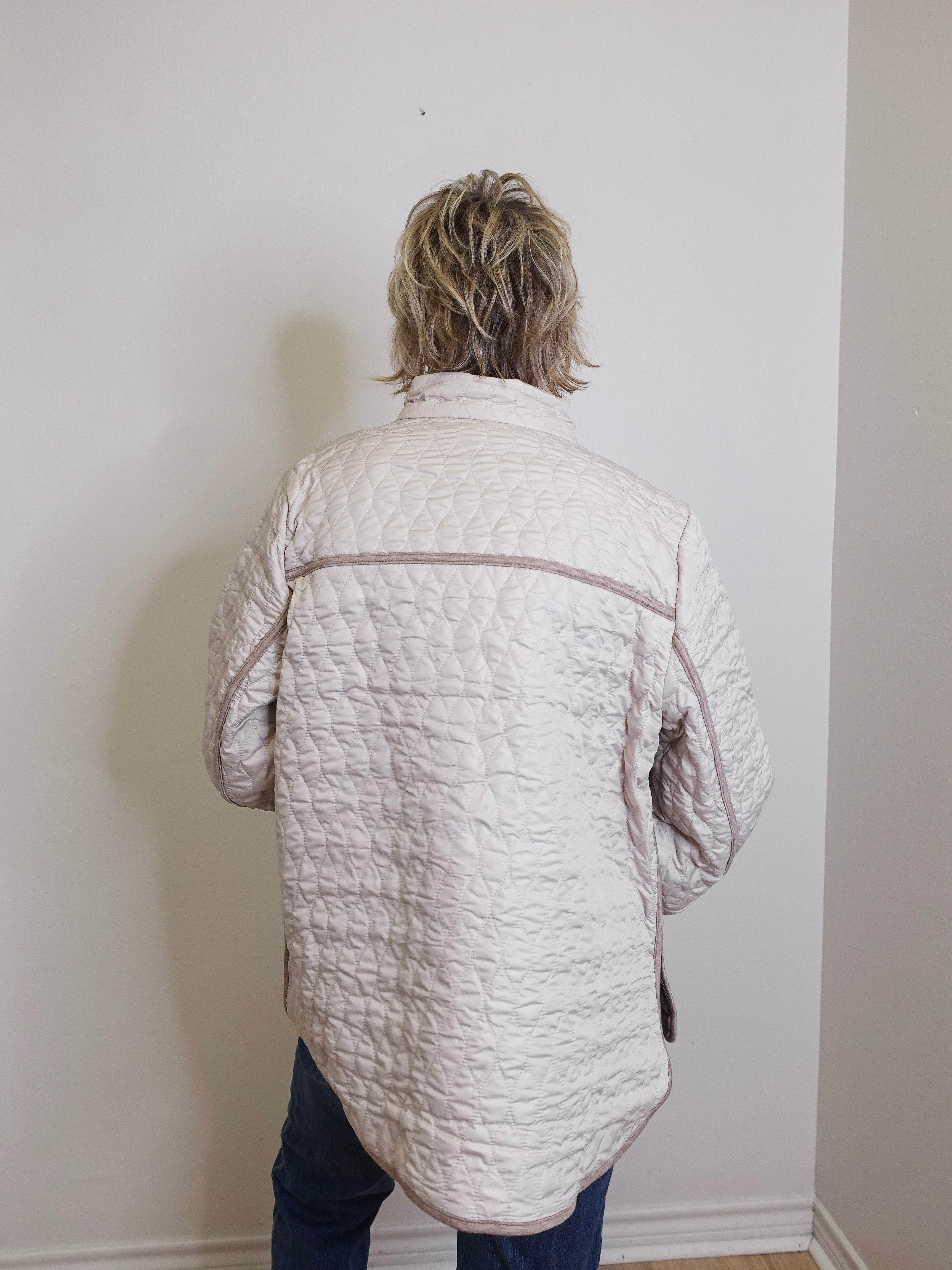 Person wearing a quilted jacket against a plain wall