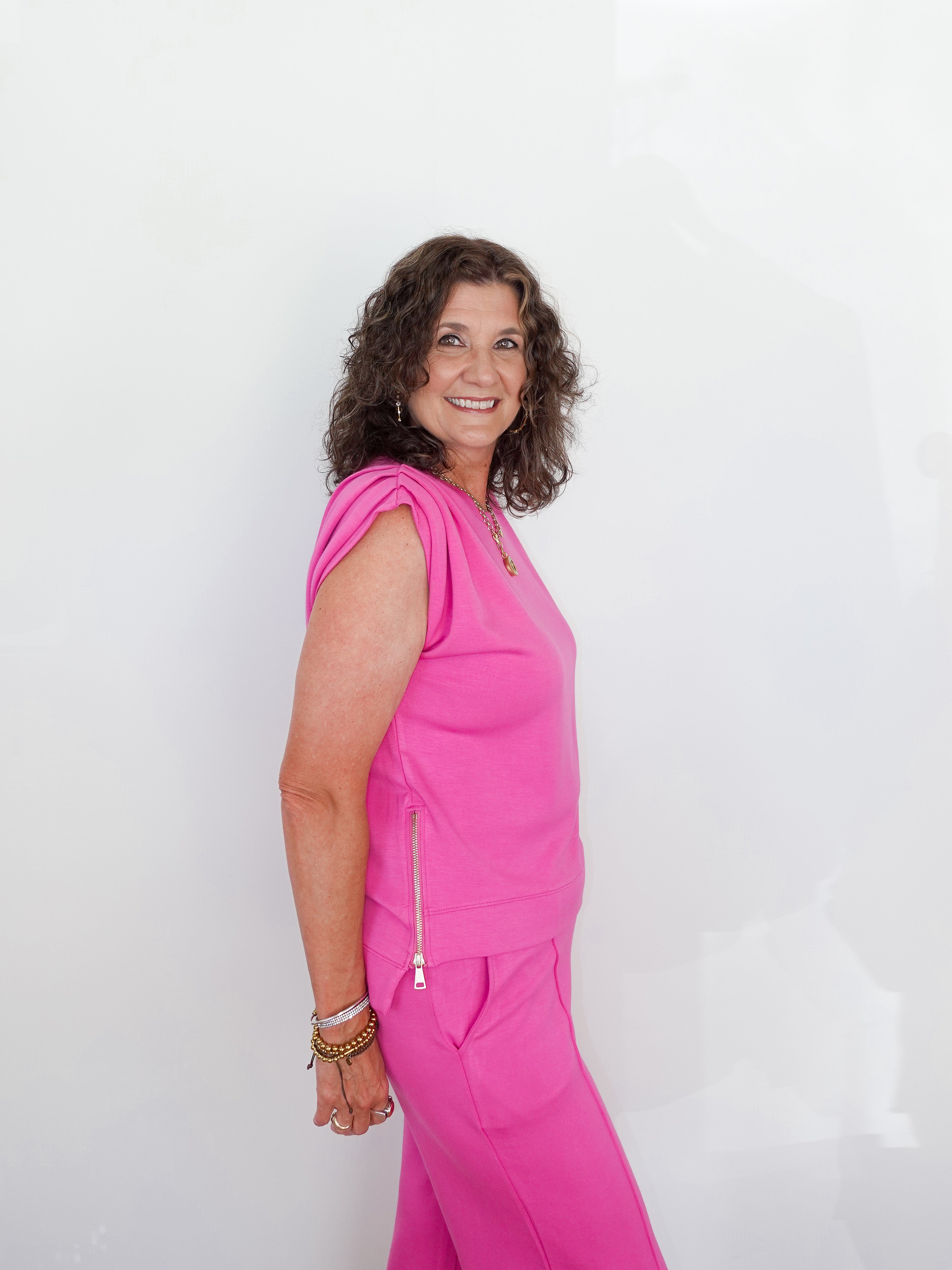 Woman wearing a bright pink outfit against a white background