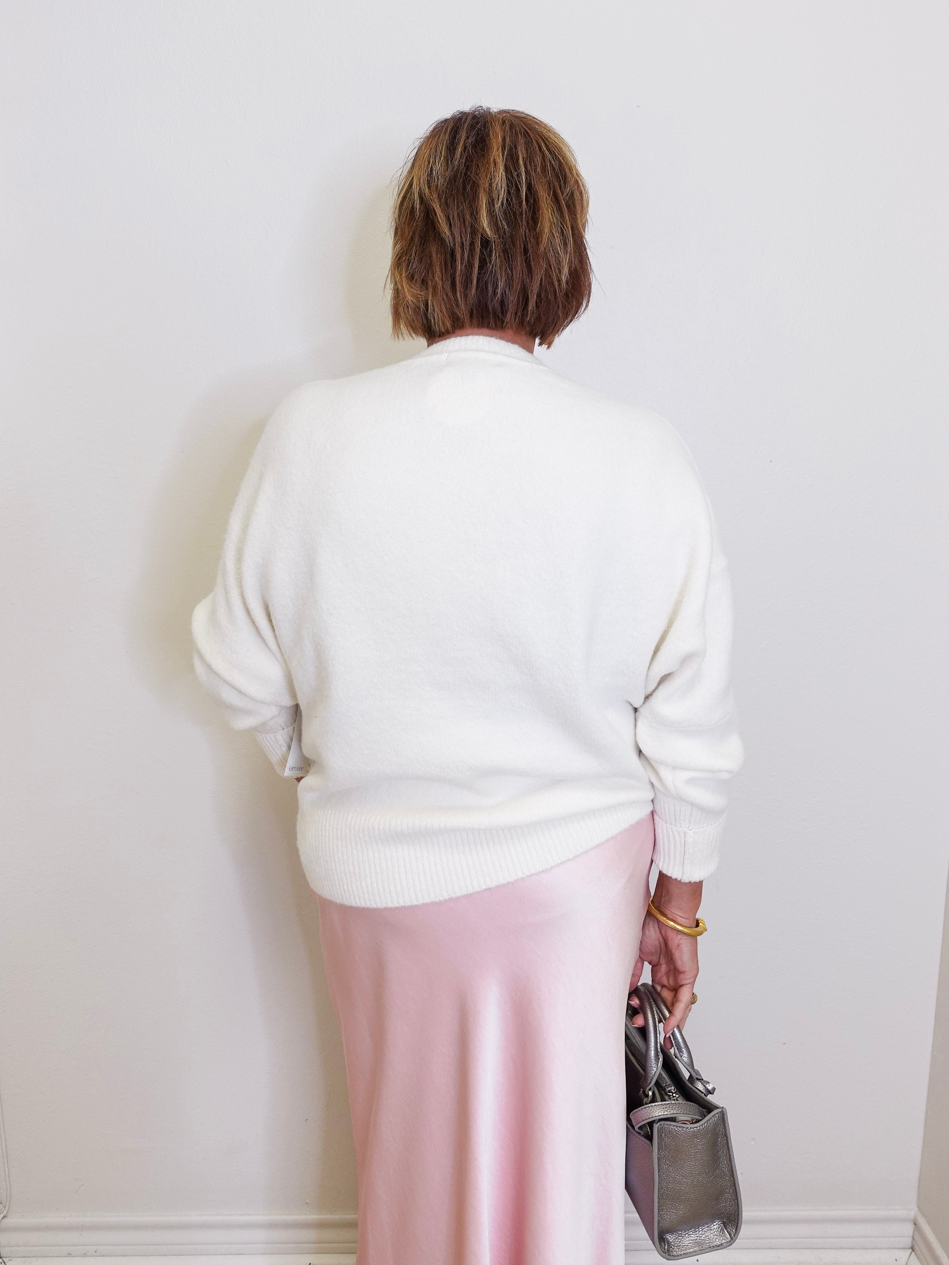 woman wearing a cream sweater against a white background. 