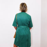 Person wearing a green dress against a white wall