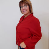 Woman wearing a red blouse and glasses against a plain background