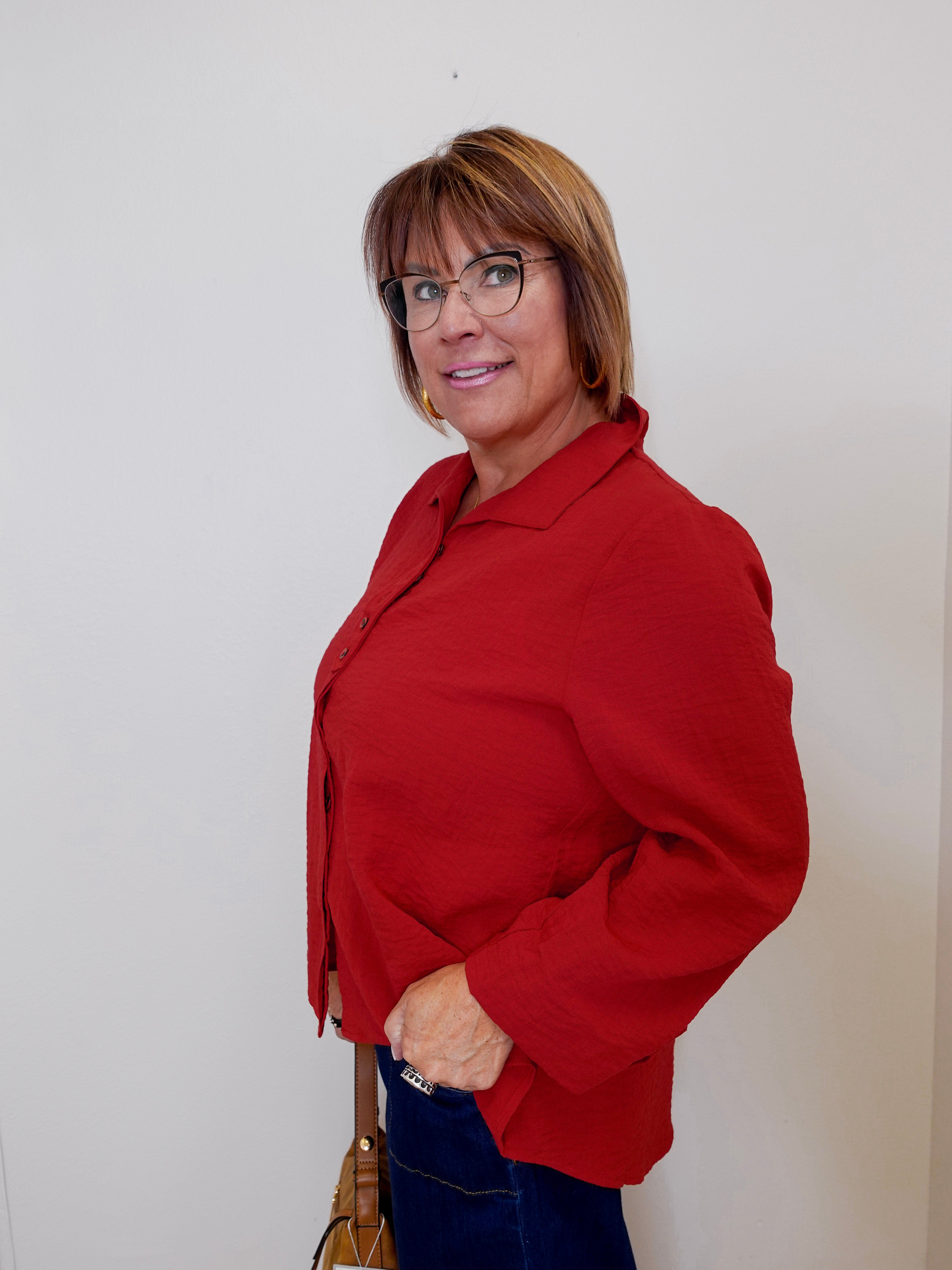 Woman wearing a red blouse and glasses against a plain background