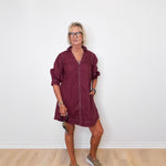 Woman wearing a burgundy dress with a white wall background