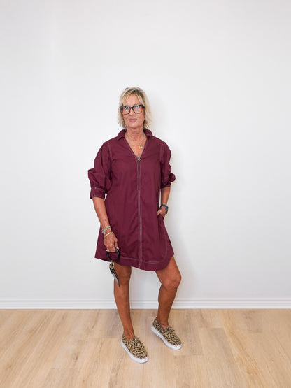 Woman wearing a burgundy dress with a white wall background