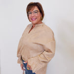 Woman wearing a beige blouse and blue jeans against a white background
