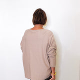 A woman wearing a v-neck jewel embellished sweater in front of a white wall.