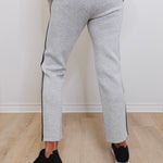 Person wearing gray jogger pants with black stripes on a light wooden floor.