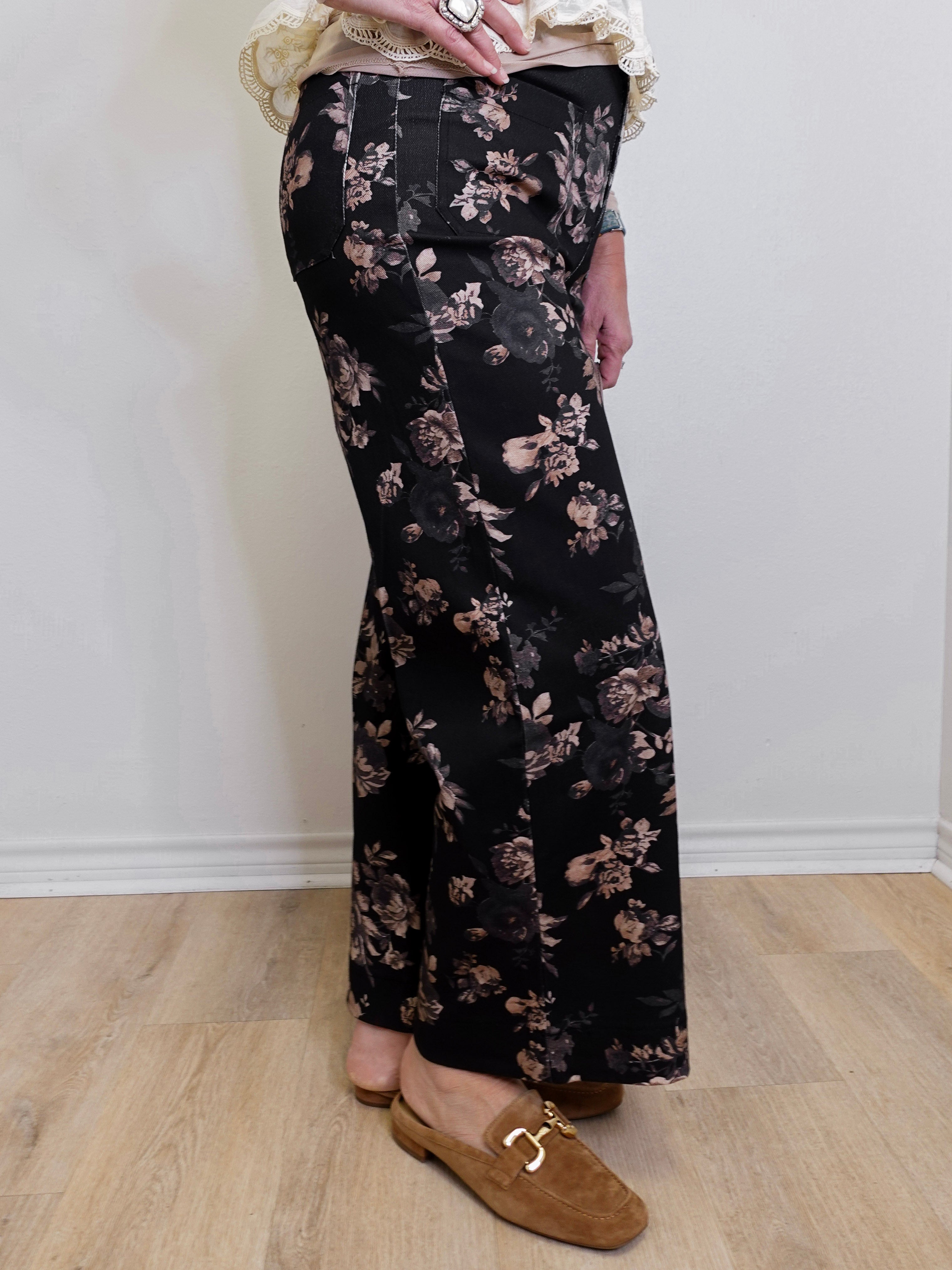 Person wearing black floral pants on a plain background