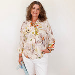 Woman wearing a floral blouse and white shorts against a plain background