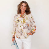 Woman wearing a floral blouse and white shorts against a plain background