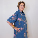 Woman wearing a blue floral dress against a white wall